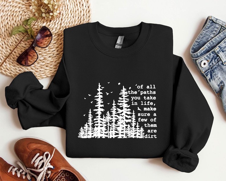 May include: Black sweatshirt with a white graphic of trees and the text "of all the paths you take in life, make sure a few of them are dirt".