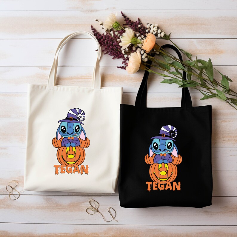May include: Two white and black tote bags with a blue cartoon character wearing a witch hat and holding a jack-o-lantern. The text "Tegan" is printed on both bags.