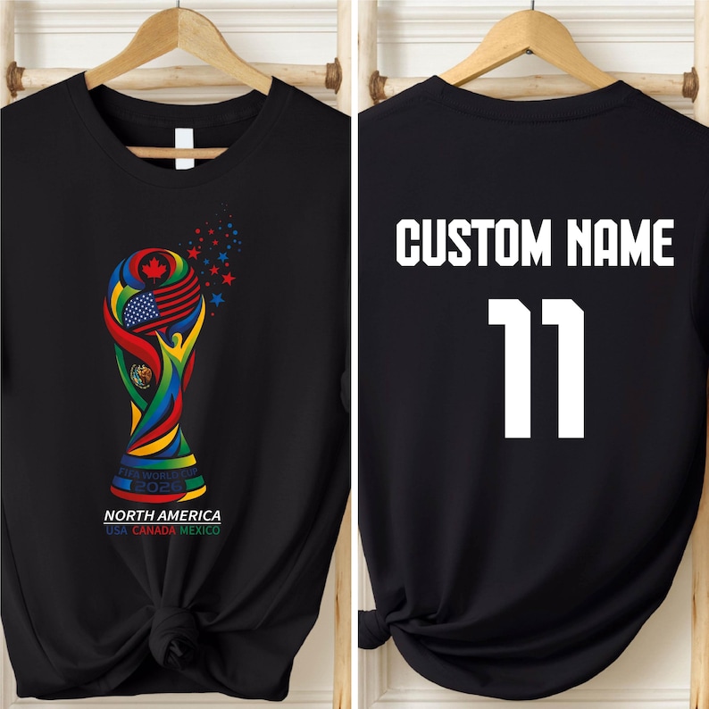 A black t-shirt with a colorful graphic of the FIFA World Cup trophy and the text "NORTH AMERICA USA CANADA MEXICO" printed on it. The t-shirt also has the text "CUSTOM NAME 11" printed on the back.