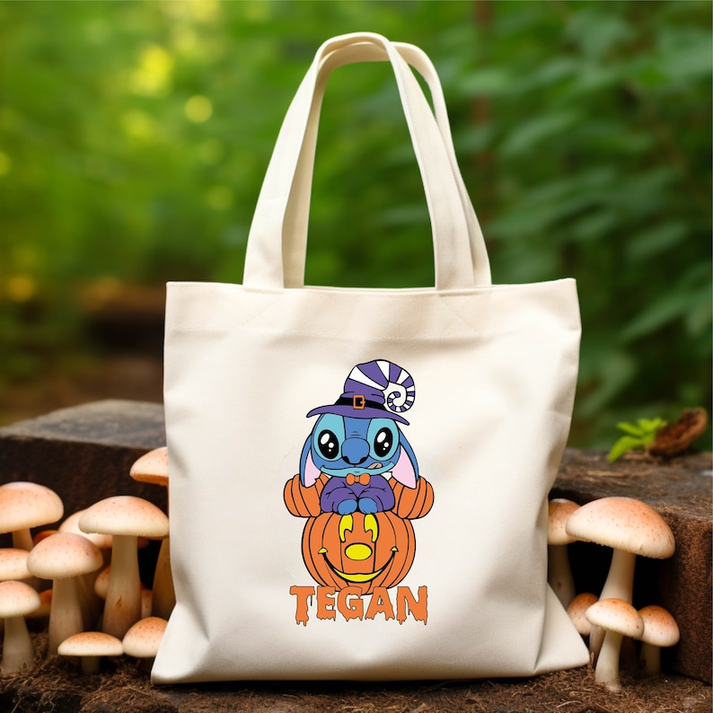May include: White canvas tote bag with a blue Stitch character wearing a witch hat and holding a jack-o'-lantern. The bag has the name "TEGAN" printed on the bottom.