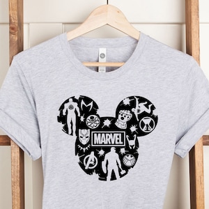 May include: Gray t-shirt with a black Mickey Mouse silhouette design featuring Marvel characters and the word "MARVEL".
