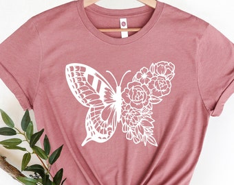 May include: A dusty rose t-shirt with a white butterfly and floral design.