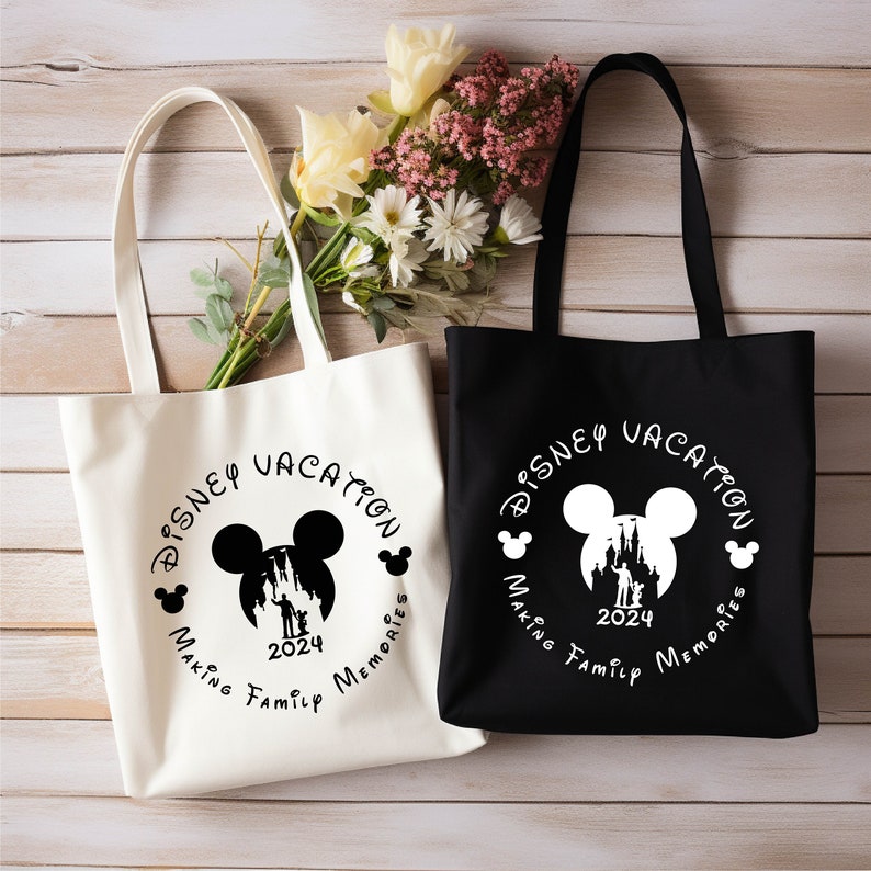Peut inclure: Deux sacs fourre-tout en toile blanche avec des poign&eacute;es noires. Les sacs pr&eacute;sentent un motif circulaire noir avec le texte "DISNEY VACATION" et une silhouette de la t&ecirc;te de Mickey Mouse avec le ch&acirc;teau de Cendrillon &agrave; l'int&eacute;rieur. Le texte "MAKING FAMILY MEMORIES" est situ&eacute; sous le cercle. L'ann&eacute;e "2024" est &agrave; l'int&eacute;rieur du cercle. Un sac est blanc avec du texte et un motif noirs. L'autre sac est noir avec du texte et un motif blancs.