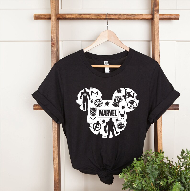 May include: Black t-shirt with a white Mickey Mouse silhouette design featuring Marvel characters, including Iron Man, Captain America, Thor, Black Panther, and more. The word "MARVEL" is printed inside the silhouette.