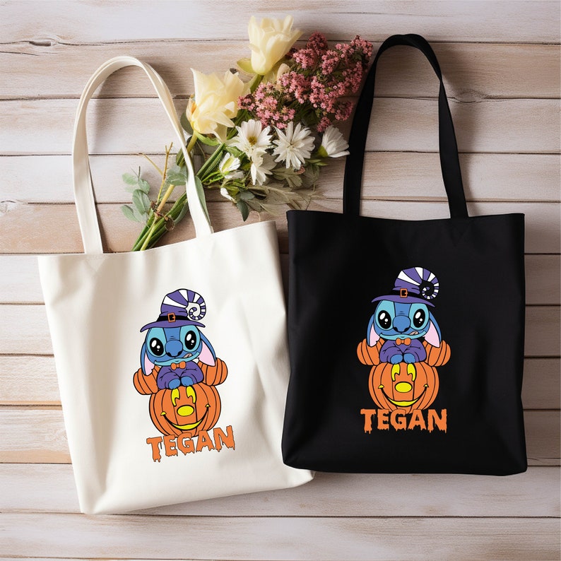 May include: Two white and black canvas tote bags with a blue Stitch character wearing a witch hat and holding a jack-o-lantern. The text "TEGAN" is printed on both bags.
