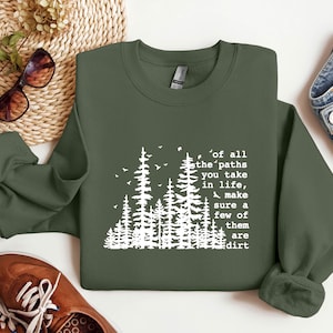 May include: A green sweatshirt with a white graphic of a forest and the text "of all the paths you take in life, make sure a few of them are dirt".