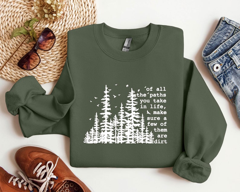 May include: A green sweatshirt with a white graphic of a forest and the text "of all the paths you take in life, make sure a few of them are dirt".