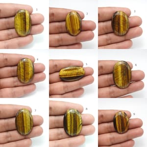 May include: Nine polished tiger's eye gemstones, each with a unique pattern of golden-brown and dark brown bands. The stones are oval-shaped and vary slightly in size. The gemstones are displayed on a neutral background.