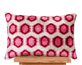 Könnte beinhalten: Ein rechteckiges Zierkissen mit einem sich wiederholenden geometrischen Muster aus rosa und dunkelroten sechseckigen Formen auf hellgrauem Hintergrund. Der Stoff hat eine weiche, strukturierte Optik mit einem sichtbaren Glanz.