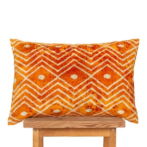 May include: A rectangular throw pillow featuring a vibrant orange velvet-like texture with a repeating white geometric pattern of horizontal zigzag lines and centered dots forming a diamond grid across the entire surface of the cushion.