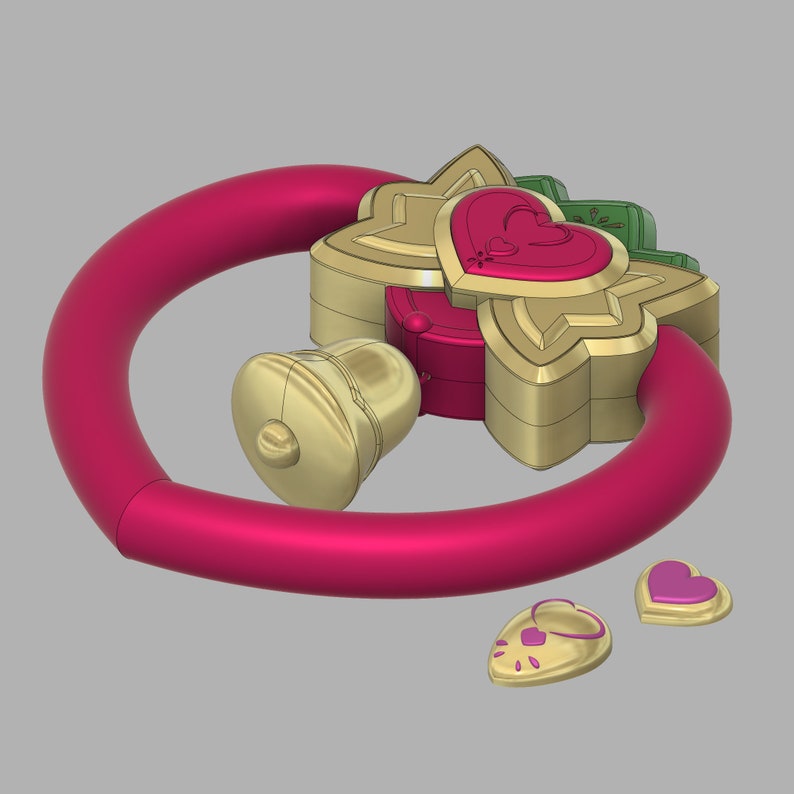 May include: A pink and gold toy ring with a bell and two heart-shaped charms. The ring is made of plastic and has a smooth surface. The bell is gold and has a small handle. The charms are gold and have a pink heart design.