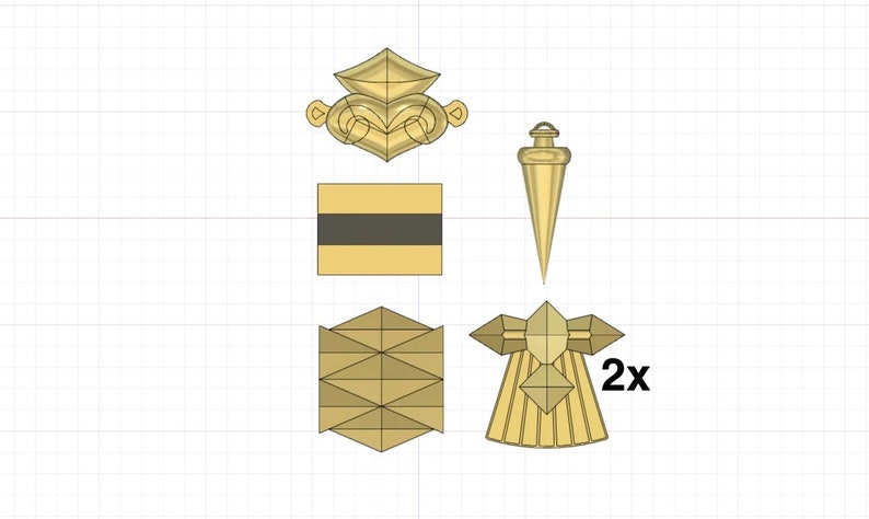 Puede incluir: Un conjunto de cinco piezas decorativas de metal de color dorado. El conjunto incluye una pieza con forma de corona, una pieza cuadrada con una franja negra, una pieza puntiaguda y dos piezas id&eacute;nticas con un dise&ntilde;o en forma de estrella. Las piezas con forma de estrella tienen una etiqueta 2x.