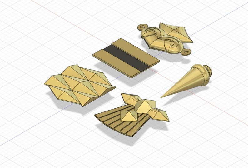 Puede incluir: Cinco adornos de metal de color dorado con dise&ntilde;os geom&eacute;tricos. Los adornos est&aacute;n dispuestos sobre un fondo de cuadr&iacute;cula blanca.