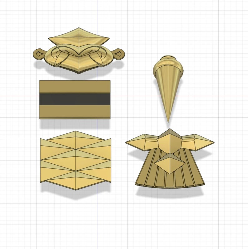 Puede incluir: Un conjunto de cuatro adornos de metal de color dorado. Los adornos tienen forma de corona, estrella, rect&aacute;ngulo y punta. Los adornos est&aacute;n todos sobre un fondo de cuadr&iacute;cula blanca.