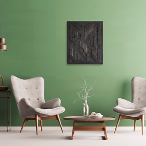 May include: Two beige armchairs with wooden legs face each other in a living room with a green wall. A black and brown geometric wall art hangs above a coffee table with a vase of white flowers.