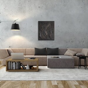 May include: A modern living room with a large sectional sofa in a light brown fabric. The sofa is arranged in an L-shape with a coffee table in the center. The coffee table has a wooden frame and two shelves. The room has a concrete wall with a black and white geometric art piece hanging on it. There is a floor lamp with a black shade in the corner of the room.