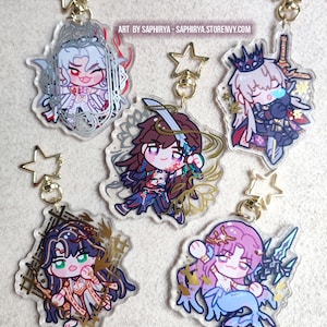 Puede incluir: Cinco llaveros de acr&iacute;lico transparente con personajes de estilo anime chibi y cierres dorados en forma de estrella. Cada dije muestra dise&ntilde;os de personajes &uacute;nicos con detalles intrincados y colores vivos. El texto ART BY SAPHIRYA - SAPHIRYA.STORENVY.COM es visible.