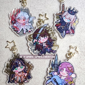 Puede incluir: Cinco llaveros de acr&iacute;lico transparente con personajes de anime estilo chibi y cierres dorados en forma de estrella. Las figuras tienen cabello blanco, marr&oacute;n, negro y rosa, y sostienen armas o accesorios. Texto: ART BY SAPHIRYA - SAPHIRYA.STORENVY.COM.
