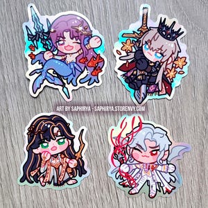 Puede incluir: Cuatro pegatinas hologr&aacute;ficas con personajes de anime estilo chibi. Una es una sirena de pelo morado con peces dorados, otra un caballero con corona y espada, una tercera de pelo oscuro y una cuarta figura de pelo blanco con cintas rojas.