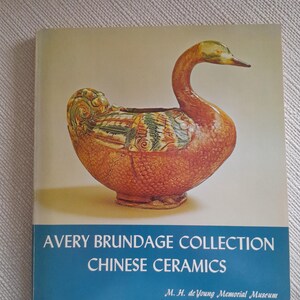 Könnte beinhalten: Buchcover mit einer Keramik-Entenskulptur mit detaillierten Mustern. Der Titel "AVERY BRUNDAGE COLLECTION CHINESE CERAMICS" steht in Weiß auf einem blauen Banner. Der Name und der Ort des Museums sind ebenfalls sichtbar.