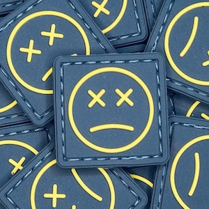 Toppa morale in PVC con faccia triste, occhio di ranger blu e giallo (1 x 1 pollice)