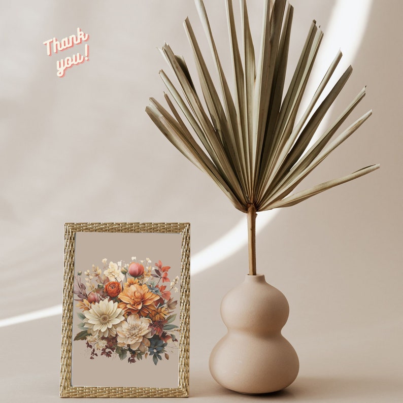 May include: A gold framed print of a vintage floral bouquet with orange, yellow, and white flowers. The print is sitting on a table next to a vase with a dried palm leaf.