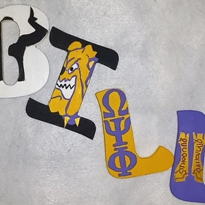 May include: Four decorative wooden letters spelling BULL. The B is white with a black silhouette, the U features a yellow bulldog face, the L displays purple Greek letters Omega, Psi, and Phi on a yellow background, and the final L is purple.