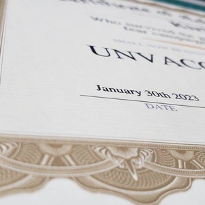 Puede incluir: Un certificado con bordes de filigrana decorativos de color beige y un fondo crema. El texto "UNV ACCINATED" se muestra de forma destacada, junto con la fecha "30 de enero de 2023". El certificado es probablemente un art&iacute;culo conmemorativo.