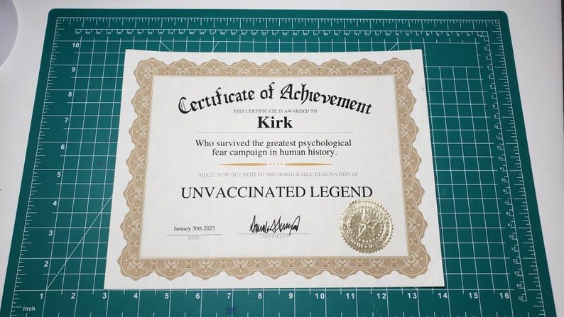 Puede incluir: Un certificado de logro con bordes ornamentados y un sello dorado. El texto dice "Certificado de Logro" y "Leyenda No Vacunada", con el nombre "Kirk" y la fecha "30 de enero de 2023". El certificado est&aacute; sobre una esterilla de corte verde.