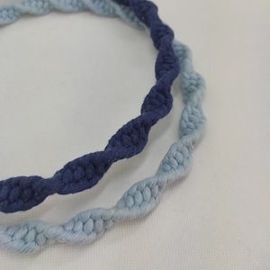 May include: Two twisted rope cords, one in a light blue color and the other in a dark blue color. The cords are intertwined and create a decorative pattern.