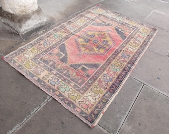May include: A vintage Turkish rug with a pink, beige, and blue color scheme. The rug has a central medallion with a geometric design and a border with floral motifs.