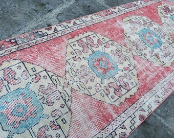 May include: A vintage rug with a faded pink background and a cream-colored pattern. The pattern features a repeating design of stylized flowers and leaves in shades of blue, pink, and cream.