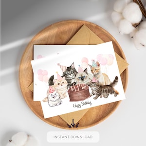 Puede incluir: Tarjeta de cumpleaños con una ilustración en acuarela de seis gatos con sombreros de fiesta, reunidos alrededor de una tarta de chocolate con velas encendidas. Globos rosas y las palabras "Happy Birthday" también están en la tarjeta.