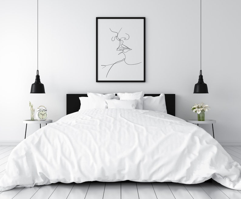 Puede incluir: Un dormitorio minimalista con una cama blanca y un cabecero negro. Dos peque&ntilde;as mesitas de noche con objetos decorativos a ambos lados de la cama. Sobre la cama, una impresi&oacute;n enmarcada de arte lineal de dos caras bes&aacute;ndose. Dos l&aacute;mparas colgantes negras.