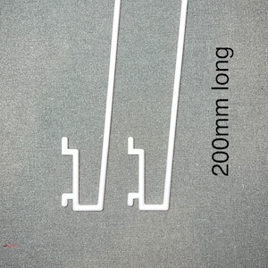 May include: Two white plastic shelf brackets, each with a 200mm long vertical support and a horizontal base. The brackets are designed to support shelves.