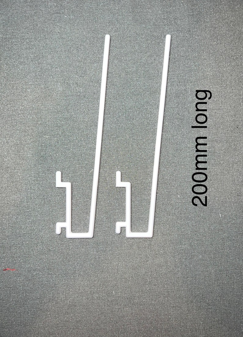 May include: Two white plastic shelf brackets, each with a 200mm long vertical support and a horizontal base. The brackets are designed to support shelves.