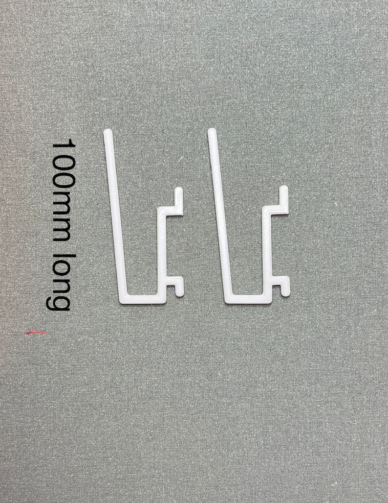 May include: Two white plastic shelf brackets, each measuring 100mm long. The brackets are designed to support shelves.
