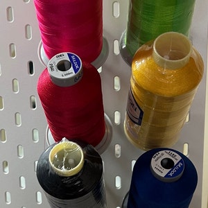 May include: Five spools of thread in different colours, including red, green, gold, black, and blue. Each spool is labelled with the brand "BRILDOR" and the text "100% Polyester".