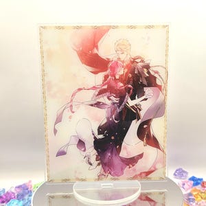 May include: A clear acrylic stand featuring a romantic anime illustration of a couple dancing. The artwork has a gold border and is set on a white rotating base surrounded by colorful decorative crystals. The image has a soft, romantic color palette.