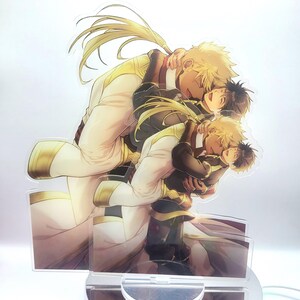 May include: A clear acrylic stand with a printed image of two anime characters embracing. The characters are both male and have blonde hair. The character in the front is wearing a black and gold outfit, while the character in the back is wearing a white and gold outfit.
