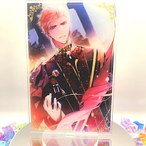May include: A clear acrylic stand with a vibrant illustration of a person in formal attire. The artwork features intricate details with red, black, and gold hues. The stand is placed on a reflective surface, surrounded by colourful gems.
