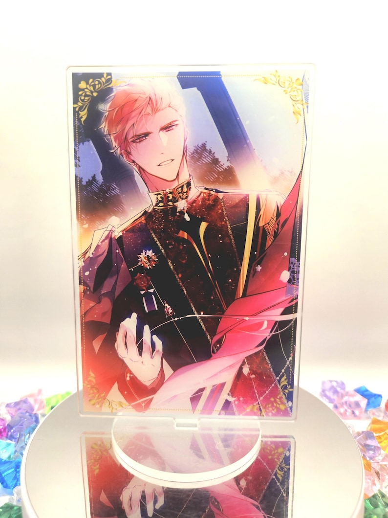 May include: A clear acrylic stand with a vibrant illustration of a person in formal attire. The artwork features intricate details with red, black, and gold hues. The stand is placed on a reflective surface, surrounded by colourful gems.