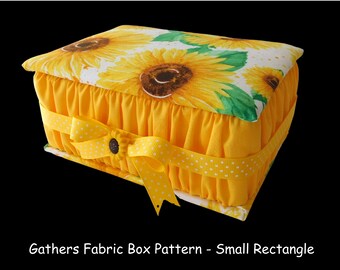 May include: A yellow fabric box with a sunflower print lid and a yellow ribbon with white polka dots. The box has a gathered fabric edge and is a small rectangle.