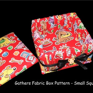 May include: A red fabric box with a dog print pattern. The box has a black ribbon tied around it and a small dog-shaped button. The box is open and the lid is sitting next to it. The lid also has the same dog print pattern.