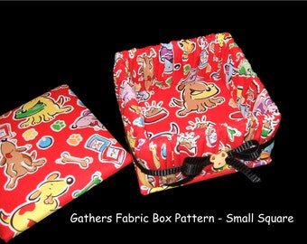 May include: A red fabric box with a dog print pattern. The box has a black ribbon tied around it and a small dog-shaped button. The box is open and the lid is sitting next to it. The lid also has the same dog print pattern.