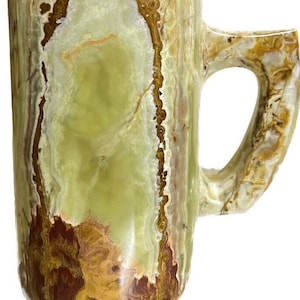 May include: A green, brown, and red onyx mug with a handle. The mug is made of natural stone and has a unique, marbled pattern.