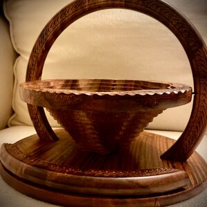 May include: A wooden bowl with a handle, the bowl is made of dark wood and has a carved design around the rim. The handle is also made of dark wood and has a carved design.