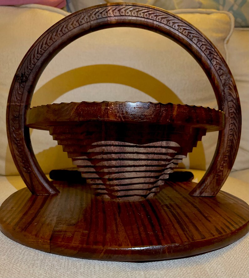 May include: A dark brown wooden serving tray with a carved heart design and a handle. The tray is made of wood and has a natural finish.