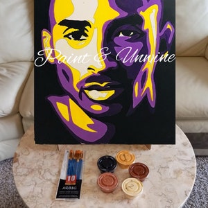 May include: A paint by numbers kit featuring a portrait of a basketball player with a purple and yellow background. The kit includes 10 paintbrushes, 5 paint pots, and a canvas.