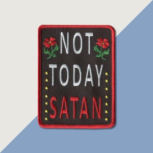 May include: A black embroidered patch with red stitching and yellow dots around the border. The patch features the text "NOT TODAY SATAN" with red flowers on either side.